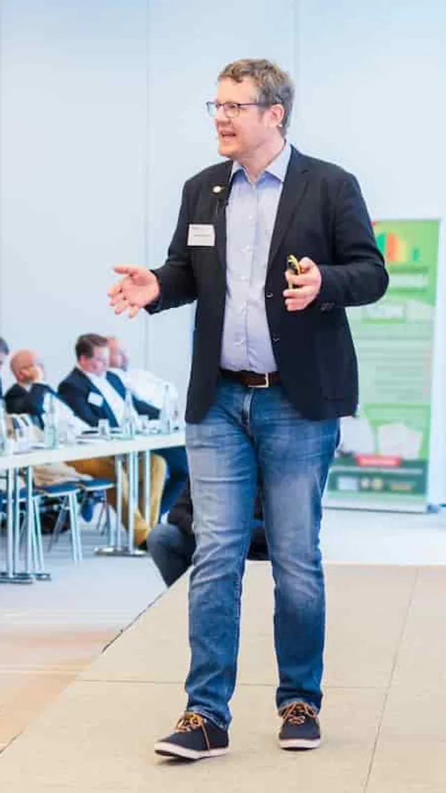 Carsten Nessler steht auf einer Bühne und hält einen Vortrag