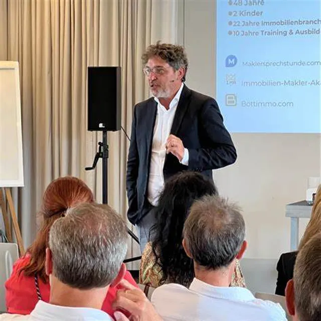 Georg Ortner steht auf einer Bühne und hält einen Vortrag