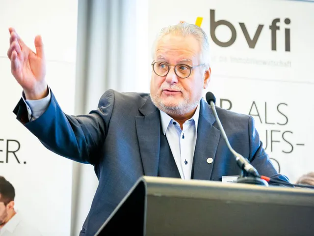 Helge Ziegler steht hinter einem Rednerpult und hält einen Vortrag